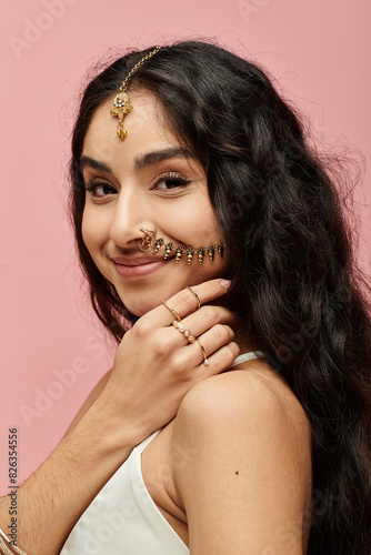 Young indian woman with nose ring striking a pose against pink backdrop.