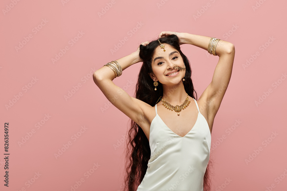 Young indian woman poses elegantly in white dress against pink backdrop. Young indian woman poses elegantly in white dress against pink backdrop.