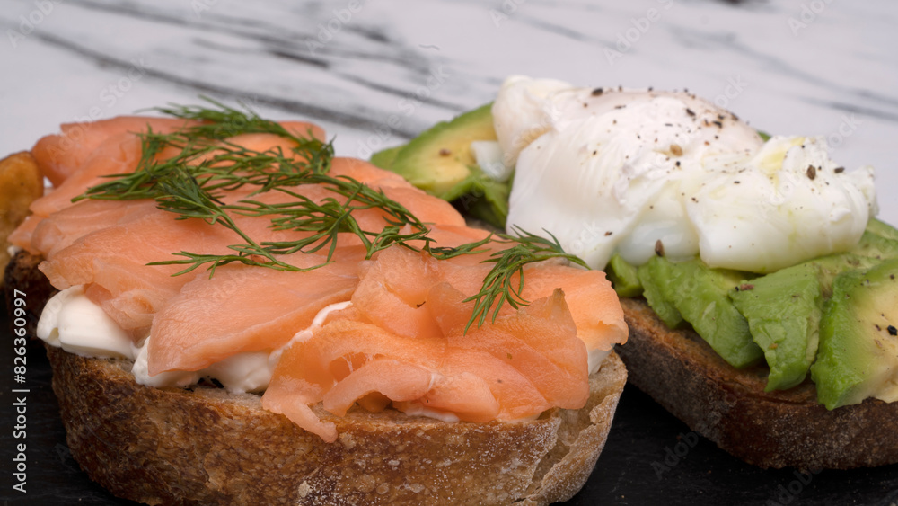 Healthy cuisine. Gourmet sandwich. Closeup view of a smoked salmon, cream cheese, sliced avocado and poached eggs sandwich in a black dish Healthy cuisine. Gourmet sandwich. Closeup view of a smoked salmon, cream cheese, sliced avocado and poached eggs sandwich in a black dish