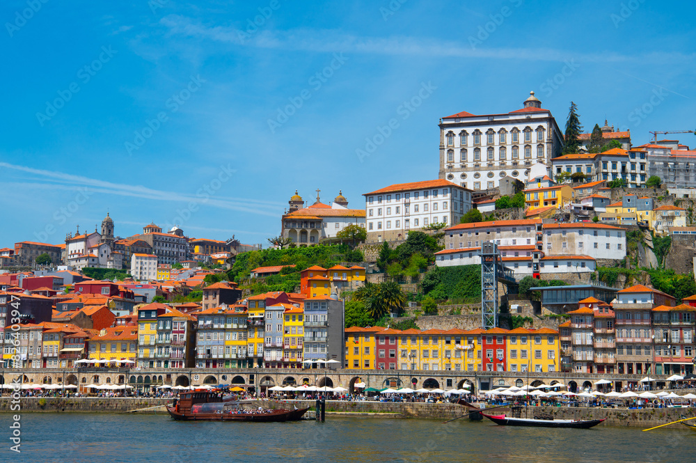 Cityscape of Porto (Oporto) over Douro River during a sunny day, Portugal. View of downtown Ribeira and embankment of Porto. Promenade view with colorful houses.