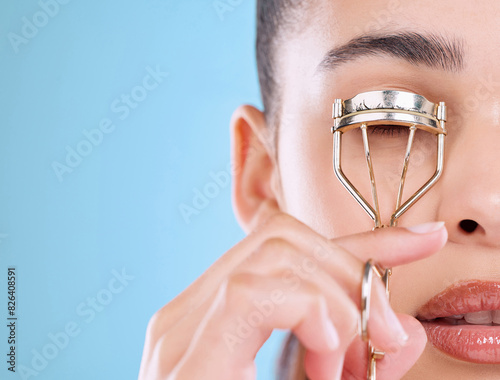 Face, makeup and woman with eyelash curler for beauty, aesthetic and glow isolated on blue studio background. Facial, metal and model with tools for lashes, skin and cosmetics application closeup