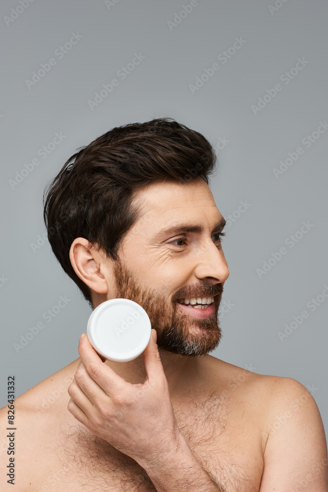 Bearded man gracefully holds a jar of cream. Bearded man gracefully holds a jar of cream.