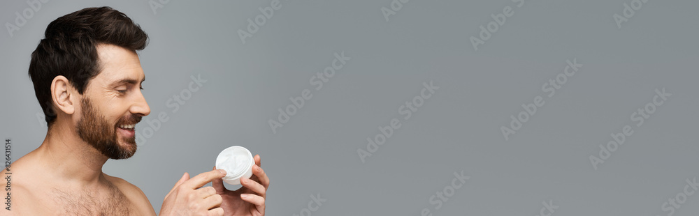 Obraz premium Shirtless man holds a jar of cream.
