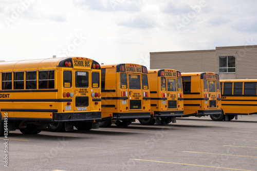 Yellow school buses lined up in a parking lot - SCHOOL BUS signage - safety warnings and signals - building in background. Taken in Toronto, Canada.