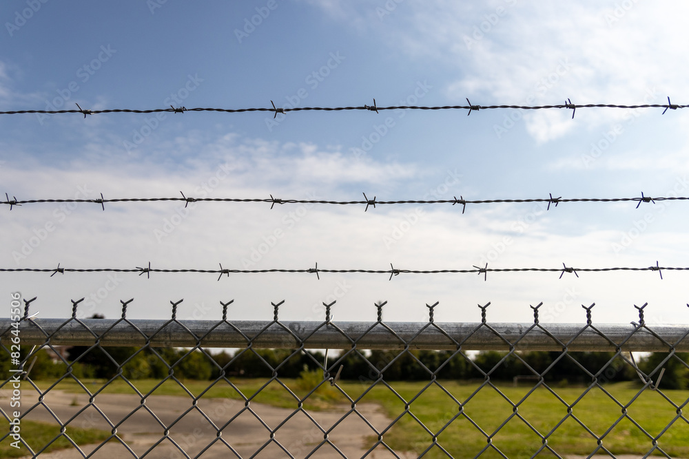 Barbed wire fence - clear sky backdrop - security boundary - restricted area - minimal cloud cover. Taken in Toronto, Canada. Barbed wire fence - clear sky backdrop - security boundary - restricted area - minimal cloud cover. Taken in Toronto, Canada.