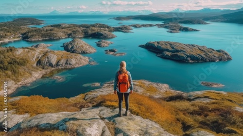 Single hiker with a backpack standing on a rock, overlooking a majestic landscape of fjords