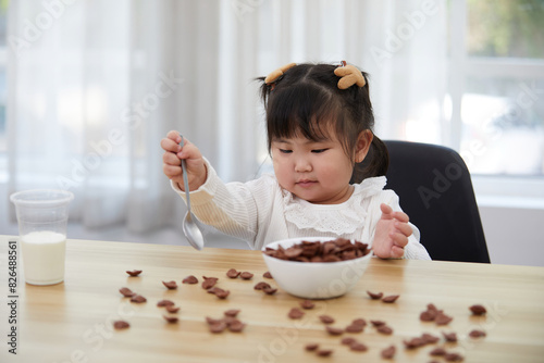 chubby child girl enjoy eating chocolate cereal on the table