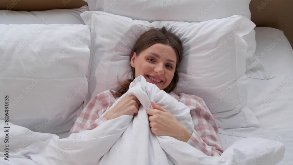 Beautiful woman peeking out from under duvet in bed, top view Beautiful woman peeking out from under duvet in bed, top view
