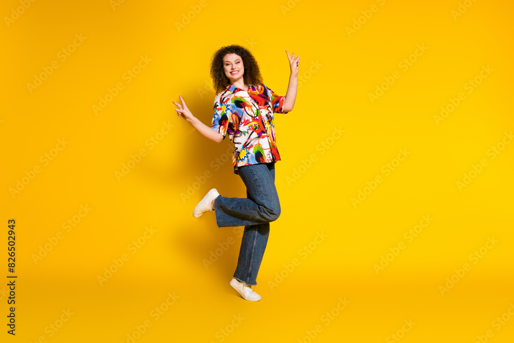 Full length photo of lovely young lady dance show v-sign dressed stylish colorful print garment isolated on yellow color background Full length photo of lovely young lady dance show v-sign dressed stylish colorful print garment isolated on yellow color background