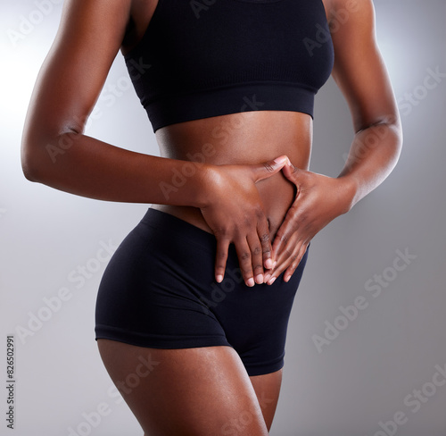 Wellness, gut health and hands of person, abdomen and diet for goal of body, lose weight and fitness. Gray background, sportswear and stomach in studio, results and digestion of athlete and exercise