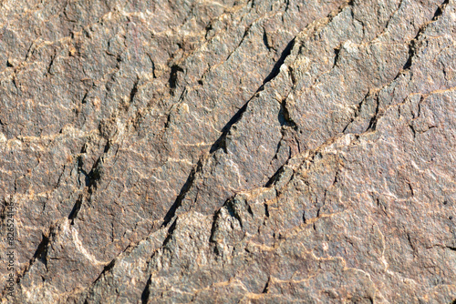 Close-up of Rough Textured Rock Surface with Natural Cracks: Nature Pattern, Geology Background, Earthy Brown Tones, Detailed Stone Texture for Design, Archaeology, Earth Science, Natural Materials photo