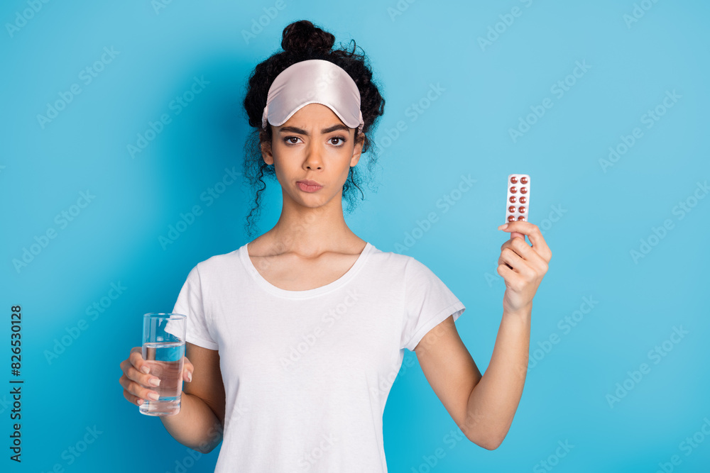 Photo of nice young woman hold pills water wear pajama isolated on blue color background Photo of nice young woman hold pills water wear pajama isolated on blue color background