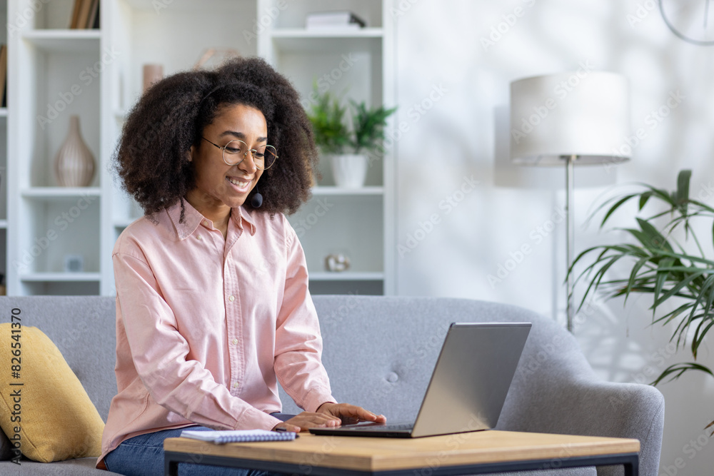 A happy woman in a modern living room, using a laptop on a sofa at home. She is smiling, working comfortably in her stylish and organized workspace, feeling focused and content A happy woman in a modern living room, using a laptop on a sofa at home. She is smiling, working comfortably in her stylish and organized workspace, feeling focused and content