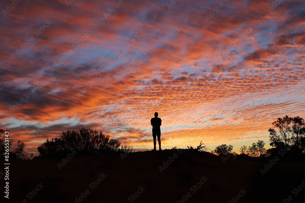 silhouetted person standing on a hilltop at sunset. silhouetted person standing on a hilltop at sunset.