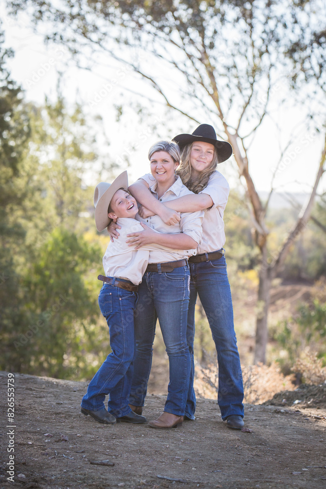 Single mother being hugged by children on family farm in drought Single mother being hugged by children on family farm in drought