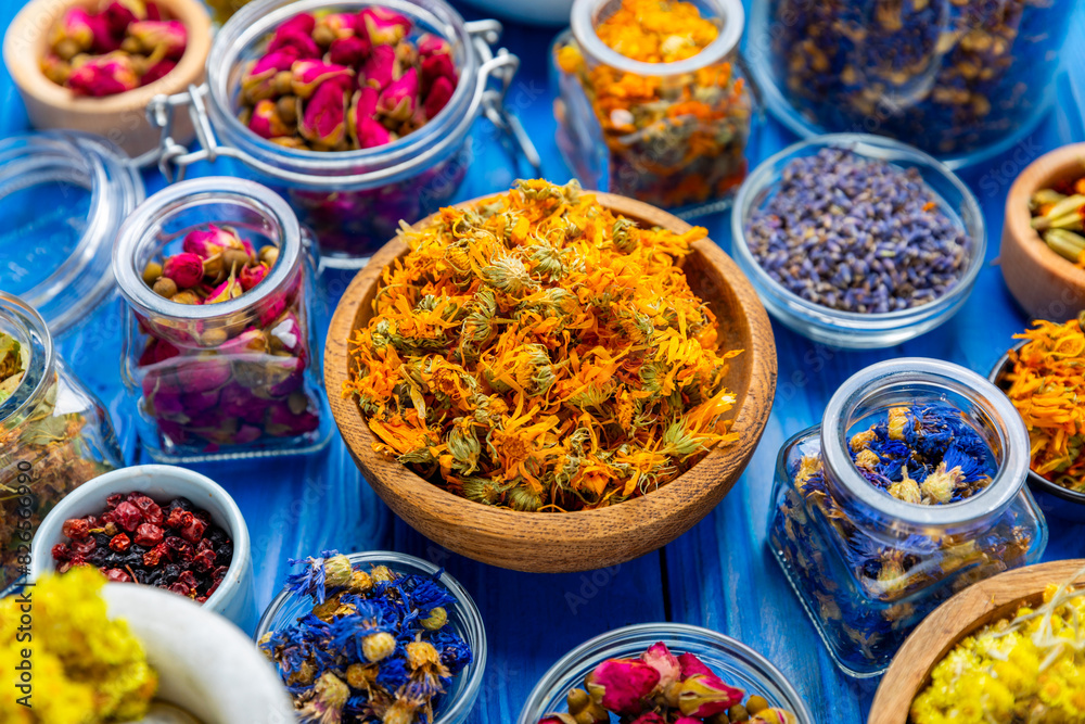 Fototapeta premium Assortment of dry herbal and berry tea on a wooden background. Tea party concept. medicinal herbs. Healing herbs.Alternative medicine.Linden, calendula, cornflowers, marigold, tansy, tea rose.