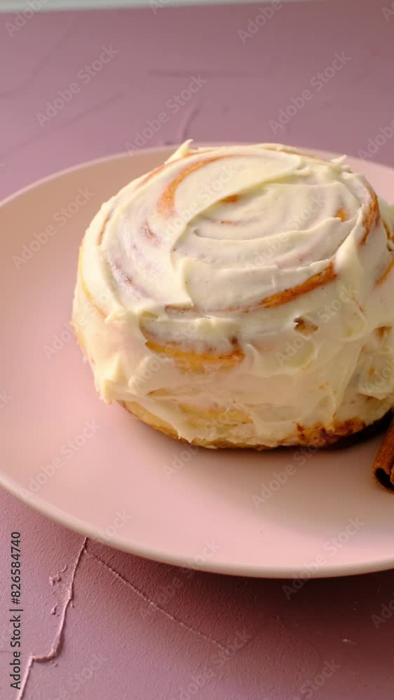 cinnamon roll on pink background and pink plate in close-up cinnamon roll on pink background and pink plate in close-up