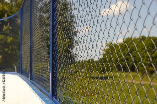 A close-up shot of a blue chain link fence of sports ground in a park © rosinka79
