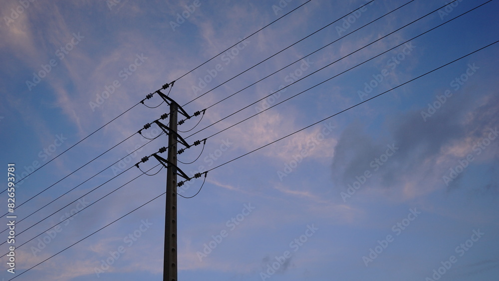 silhouette of metallic electric tower against cloudy sky