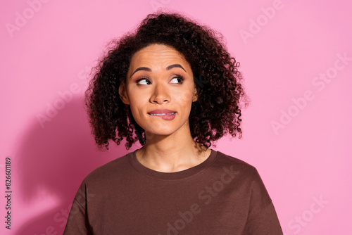 Portrait of pretty young lady bite lip look empty space wear brown t-shirt isolated on pink color background