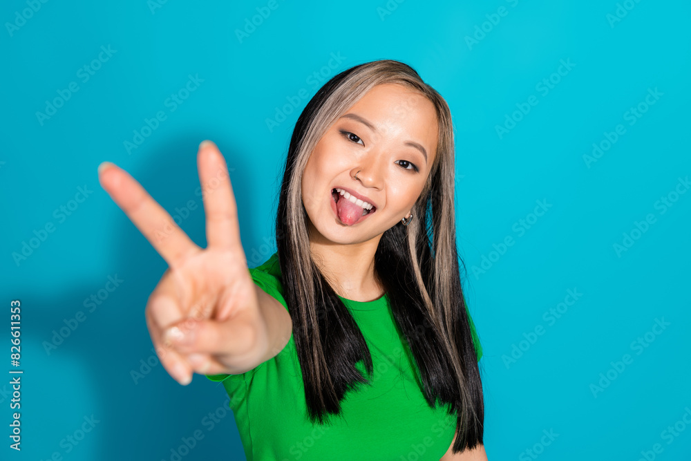 Portrait of nice young girl show tongue v-sign wear t-shirt isolated on turquoise color background Portrait of nice young girl show tongue v-sign wear t-shirt isolated on turquoise color background