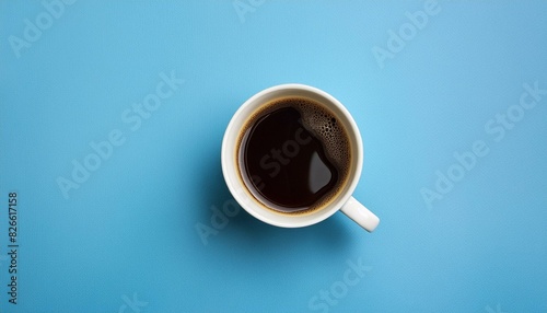A cup of coffee seen from above on a plain blue table top.