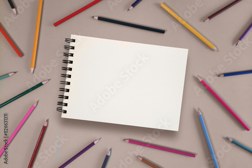 Mockup of open drawing pad with copy space school theme on background of colorful pencils. Selective focus. Space for study and creativity.