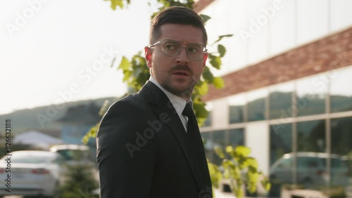 Worried businessman in suit with glasses stand near modern building looking around feel nervous at sunshine. Man entrepreneur. Camera moving around
