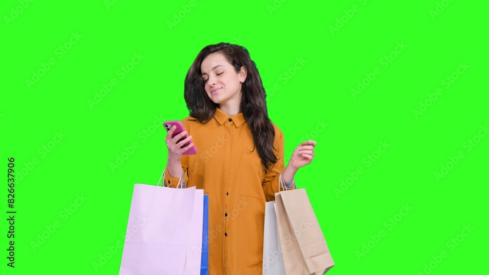 Smiling woman with shopping bags typing on the smartphone on the chroma key