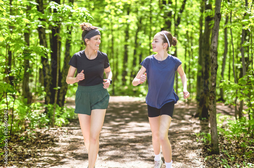 A mother and daughter exercising and jogging together at an outdoor park having great fun