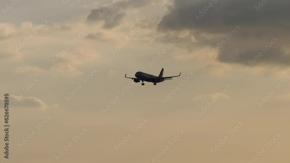 Long shot of a jet aircraft with landing gear extended approaching to land. Airliner silhouette with cloudy sunset sky Long shot of a jet aircraft with landing gear extended approaching to land. Airliner silhouette with cloudy sunset sky