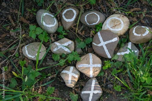 Painted pebbles X O lying in the grass by the river Berunka. Czech photo