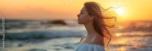 A serene woman watches the sunset by the ocean, her hair flowing in the golden light, creating a reflective and tranquil atmosphere at the calm sea beach. Filled with peace and relaxation