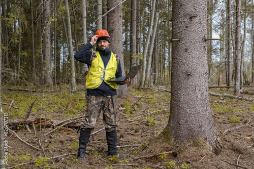 Forest engineer works in the forest with a computer. Forestry engineer. © Sergei