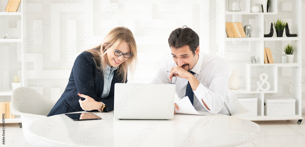 Two concentrated business people working at the desk on laptop in the office Two concentrated business people working at the desk on laptop in the office
