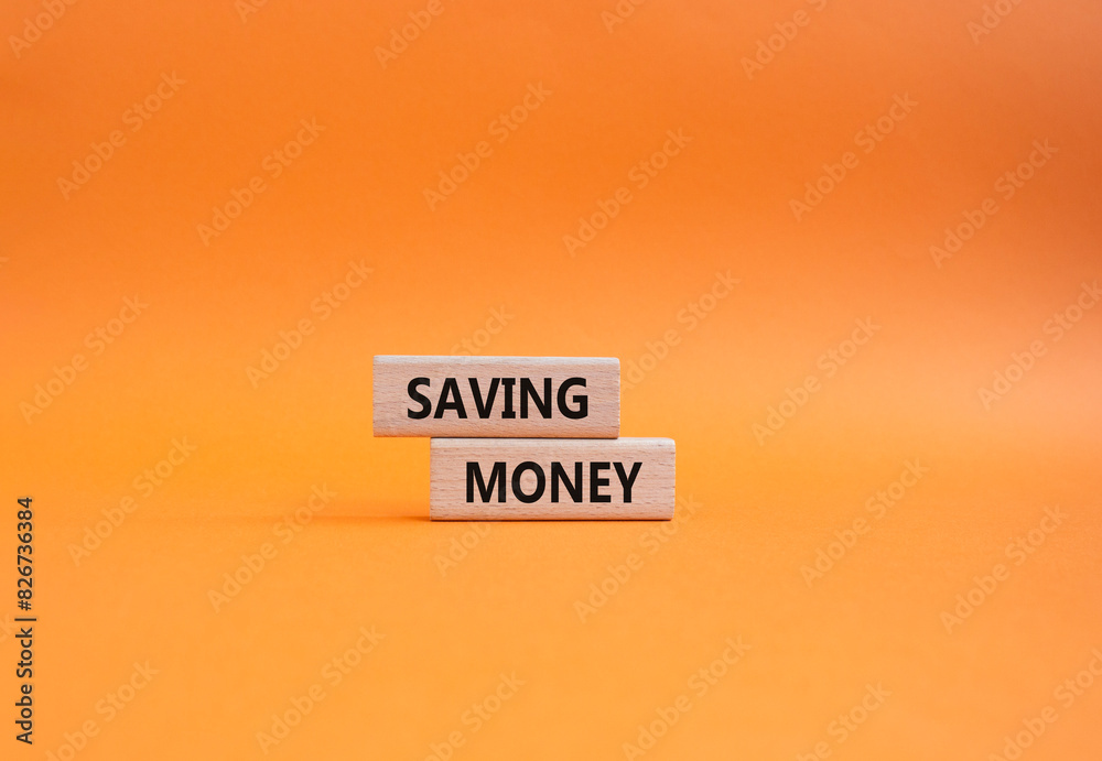 Saving Money symbol. Concept word Saving Money on wooden blocks. Beautiful orange background. Business and Saving Money concept. Copy space Saving Money symbol. Concept word Saving Money on wooden blocks. Beautiful orange background. Business and Saving Money concept. Copy space