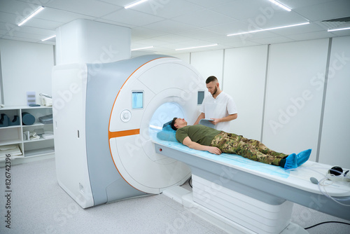 Technologist preparing military patient for upper extremity joint MRI photo