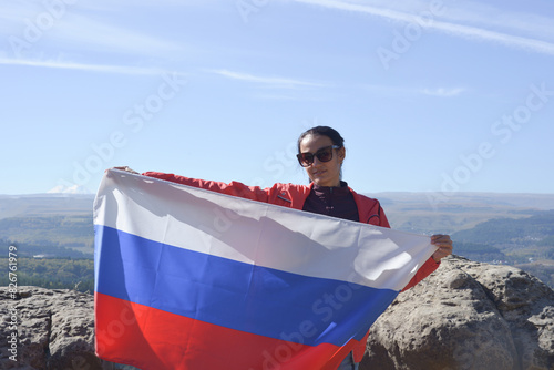 Obraz na płótnie The Russian flag is on the shoulders of a girl standing against the backdrop of the Caucasus mountains. Unity Day in Russia. w salonie