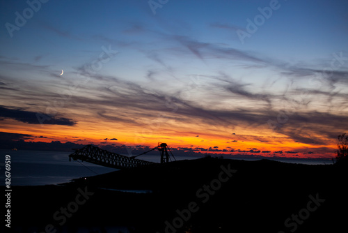 Red-orange sky at sunset in twilight evening with dark clouds and moon. Nature sky. Background, horizon golden sky, sunrise cloud magnificent, twilight sky.