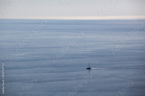 A small sailing boat sails on the sea surface of the Adriatic Sea. Balkans. View from above. Montenegro. Budva. Horizontal.