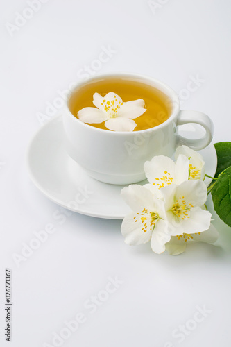 Cup with green tea and jasmine flowers on a white background.