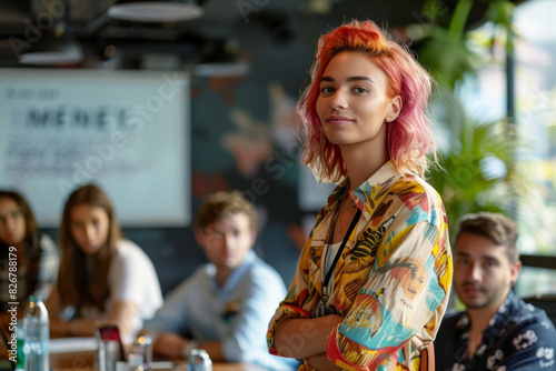 A queer with pink hair stands in front of a group of people at work