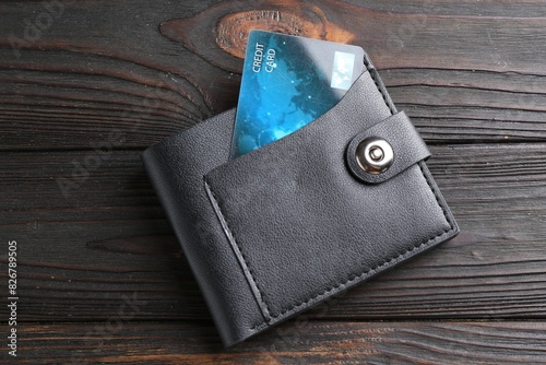 Credit card in leather wallet on wooden table, top view
