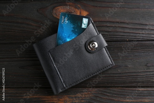 Credit card in leather wallet on wooden table, top view