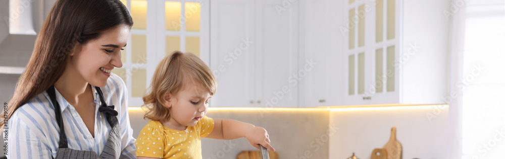 Mother and her little daughter cooking together in kitchen, space for text. Banner design Mother and her little daughter cooking together in kitchen, space for text. Banner design