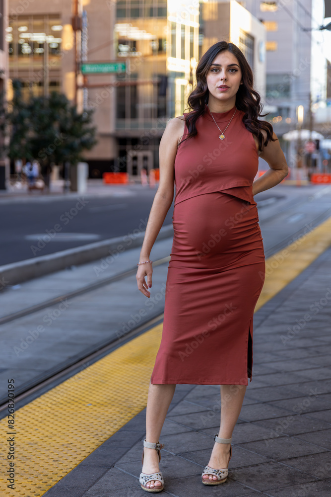 Fototapeta premium Portrait of a pregnant woman in a red dress in a maternity shoot in Downtown Phoenix, Arizona.
