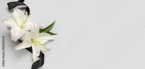 Fototapeta Naklejka Na Ścianę i Meble -  Black funeral ribbon and lily flowers on white background with space for text