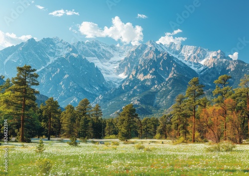 Scenic view of majestic snow-capped mountain range with lush green forest and meadow under bright blue sky with fluffy clouds