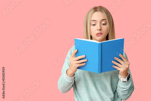 Beautiful young thoughtful woman with book on pink background