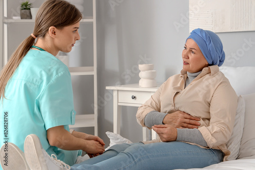 Mature woman after chemotherapy with nurse in bedroom. Stomach cancer concept